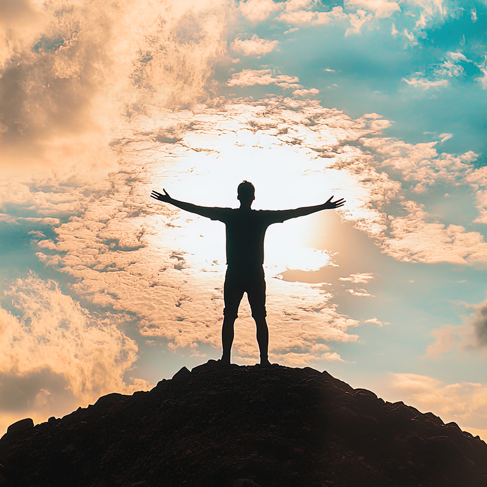 A silhouette of a person standing on top of a hill with arms stretched wide open against a dramatic sky at sunrise. Pathfinder Oncology: Exceptional outcomes in advanced cancer.